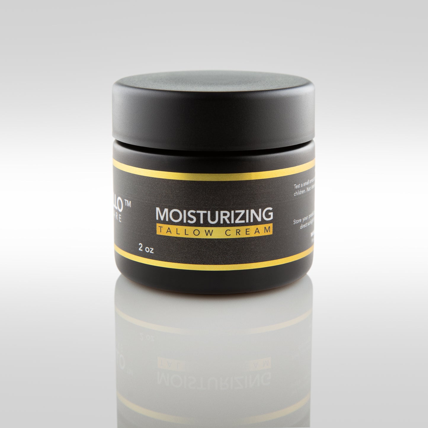 Jar of moisturizing tallow cream with black lid and label on a reflective surface.